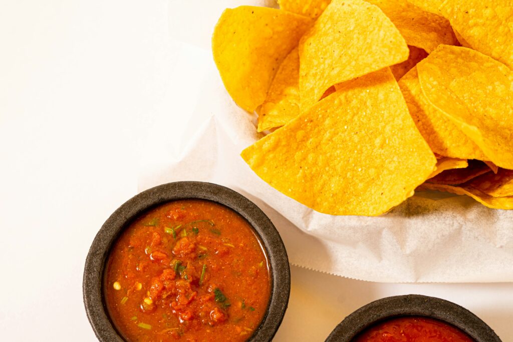 tortilla chips next to homemade salsa in a bowl