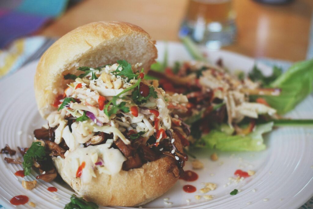 a pulled pork slider with coleslaw on a white plate