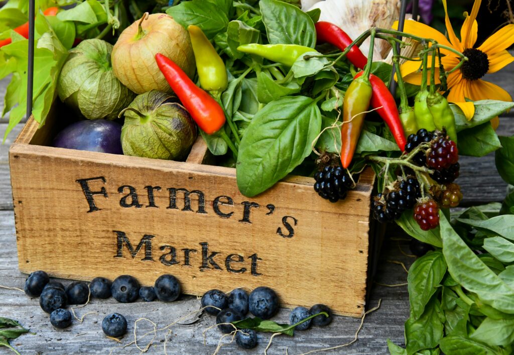 various kinds of produce in a wooden crate that says farmers market