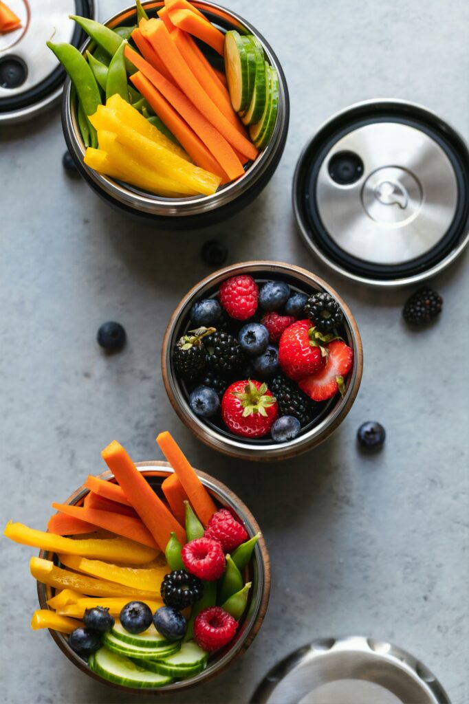 three bowls with carrots, bell peppers, and berries in them 